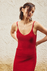 Woman wearing a red dress against a textured beige wall