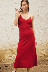 Woman wearing a red dress standing against a textured wall.