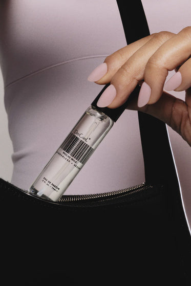 Person opening a black bag with a silver bottle inside, featuring a visible brand name.