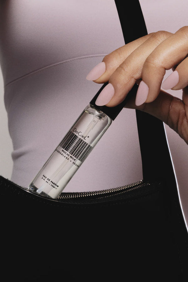 Person opening a black bag with a silver bottle inside, featuring a visible brand name.