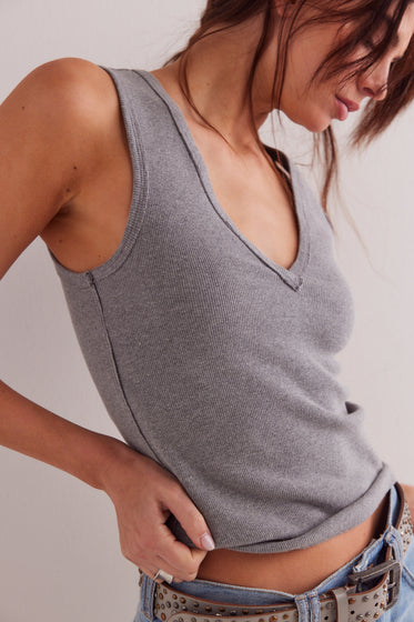 Person wearing a gray tank top with a neutral background