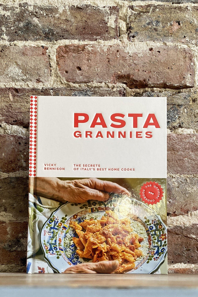 Cookbook titled 'Pasta Grannies' on a brick wall background