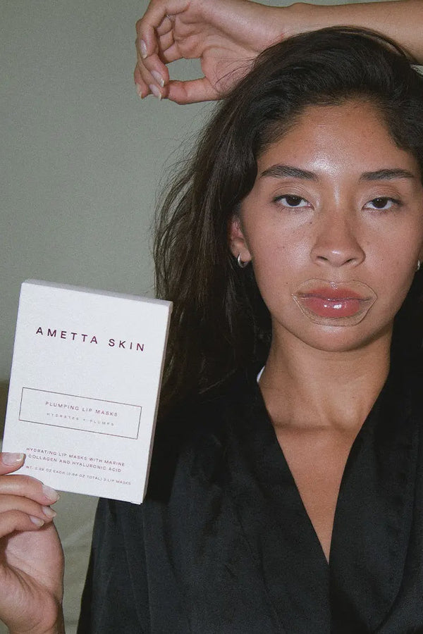 Woman holding a 'Ametta Skin' product packaging against a neutral background