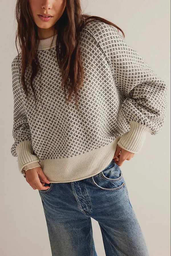 Person wearing a patterned sweater and jeans against a plain background