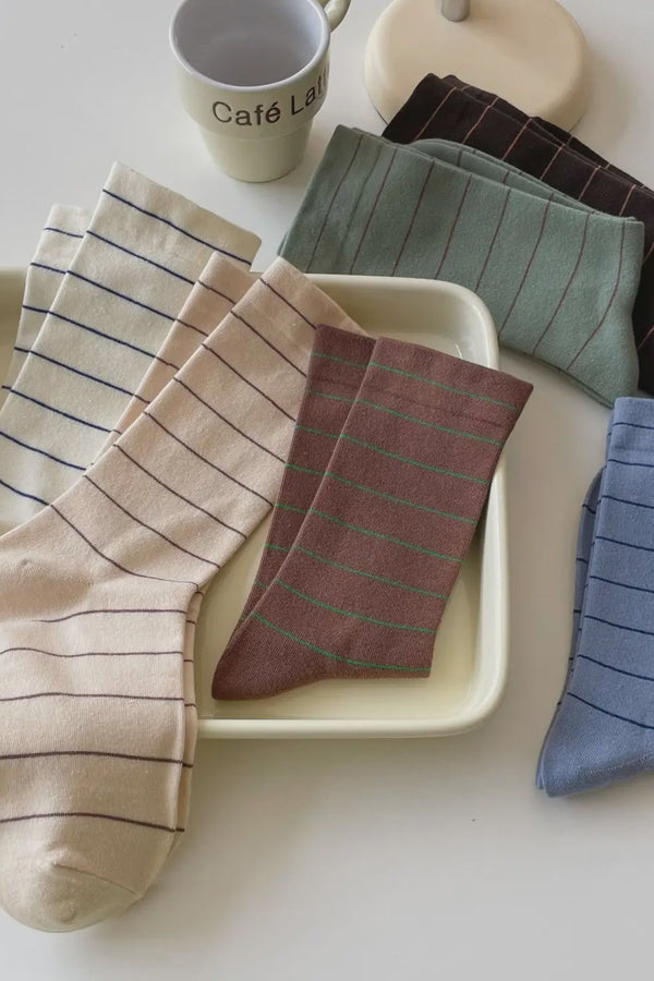 Set of striped socks on a tray with a cup and book in the background