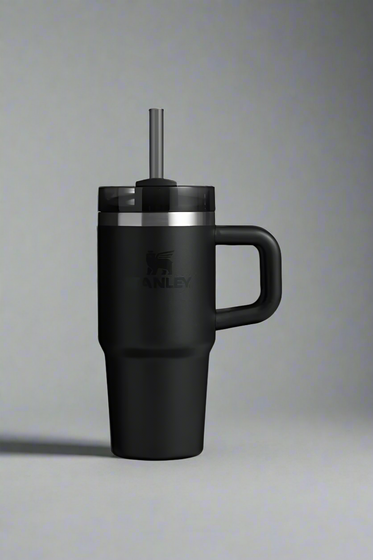 Black insulated mug with handle and straw lid on a light gray background