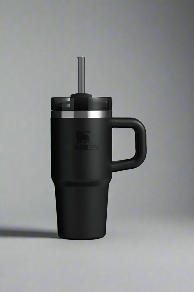Black insulated mug with handle and straw lid on a light gray background