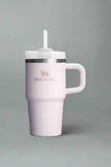 Pink insulated mug with handle and straw lid on a light gray background