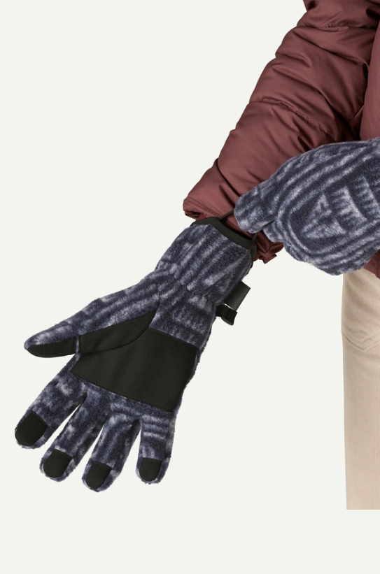 Person wearing patterned gloves and a brown jacket on a white background