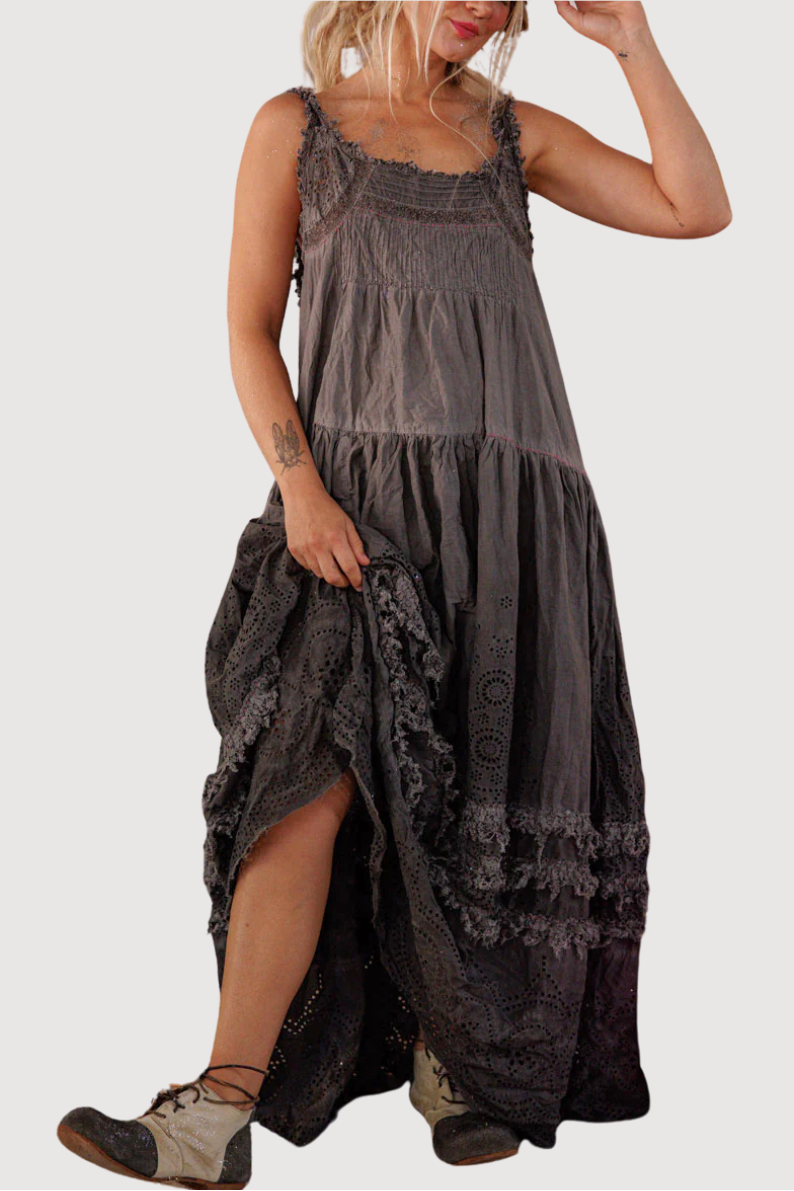 Woman wearing a long, dark dress with lace details on a white background