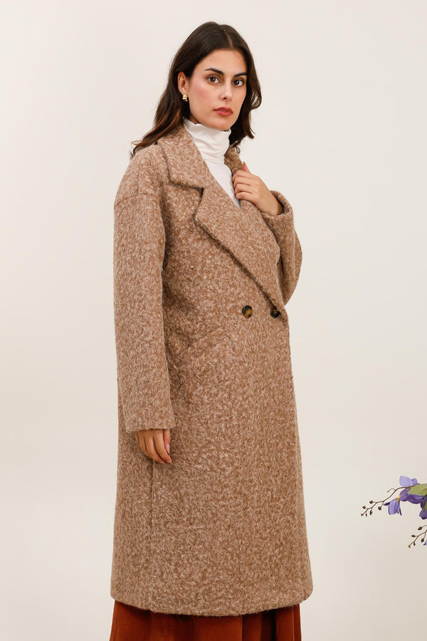 Woman wearing a long brown coat on a white background