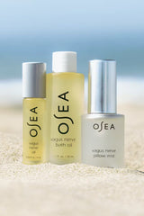 Three OSEA products on a sandy surface with a blurred beach background