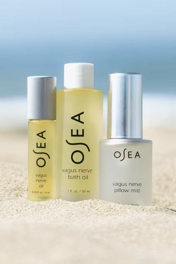 Three OSEA products on a sandy surface with a blurred beach background