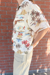 Person wearing a colorful tropical shirt with a brick wall background