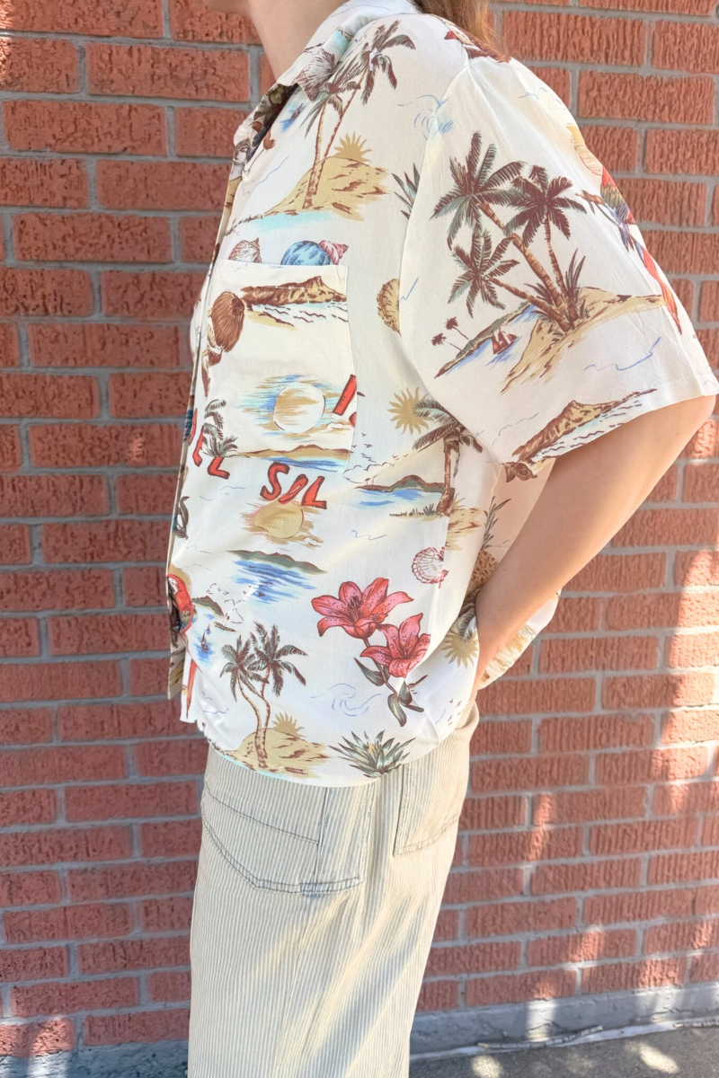 Person wearing a colorful tropical shirt with a brick wall background